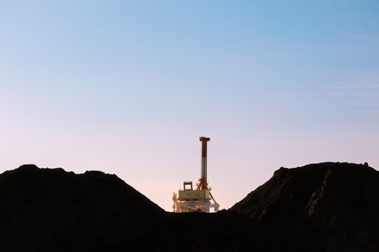 Industrial Silhouette Composed of Mineral Mounds and Heavy Machinery.