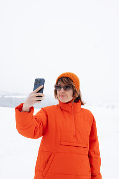 Portrait Of Woman In Orange Jacket Standing Outdoors And Taking Photo