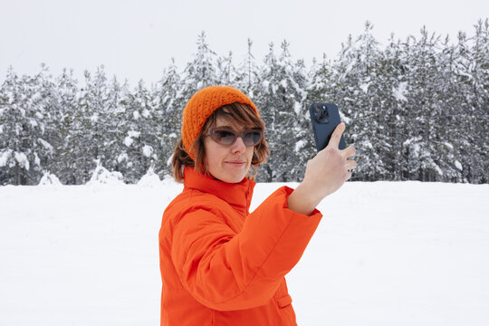 Portrait Of Woman In Orange Jacket Standing Outdoors And Taking Photo