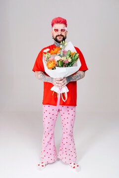 A man holds a bouquet of flowers in his hands.