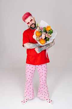A man holds a bouquet of flowers in his hands.