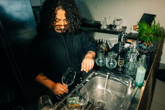 Bartender Cleans Glasses at Busy Bar During Evening Shift