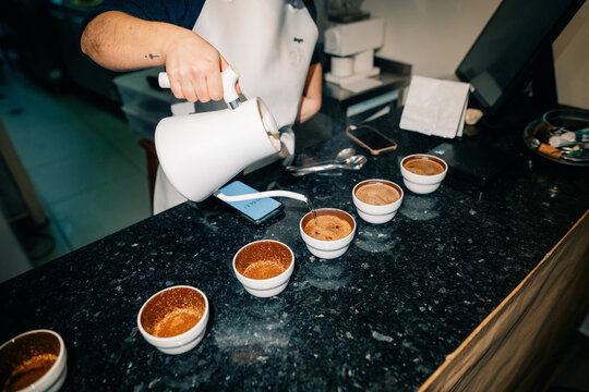 Barista Pours Hot Coffee Into Cups in Busy Cafe