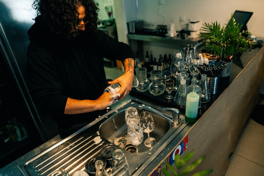 Bartender Cleans Glasses at Busy Bar During Evening Shift