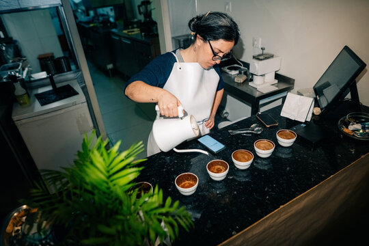 Barista Pours Coffee Into Cups in a Cafe Setting