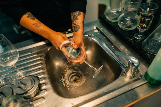 Person Washing a Glass in a Kitchen Sink During Daytime Hours