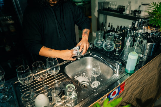Bartender Washes Glasses at Busy Bar in Urban Setting