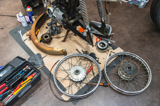 Disassembled Motorcycle Parts and Toolkit on Workshop Floor