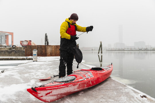 Kayaker Preparing Gear on a Snowy Urban Waterfront