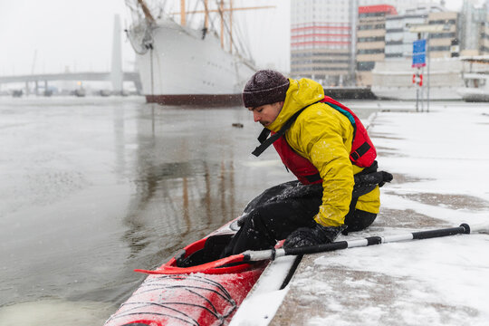 Adventurer Boarding Red Kayak on a Frozen City Dock
