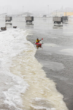 Kayaker Navigating Through Narrow Ice Channel in Frozen Harbor