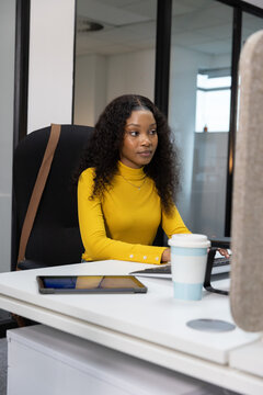 Workstation is showing keyboard, tablet, travel cup, monitor and high-back chair near window