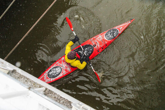 Red Kayak Passing Under Steel Gangway in Winter Harbor