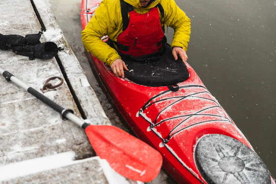 Close-up of Kayaker Conducting Final Gear Check on Snowy Dock