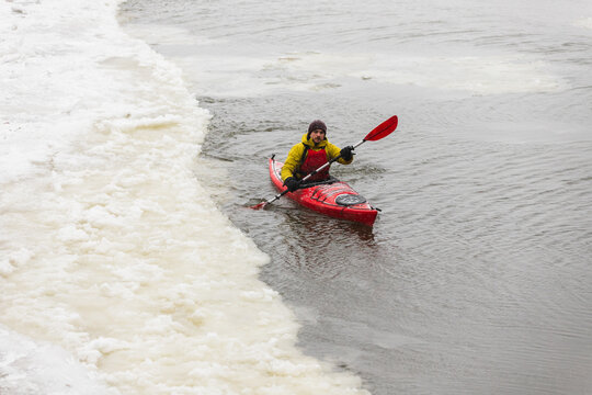 Kayaker Navigating Through Narrow Ice Channel in Frozen Harbor