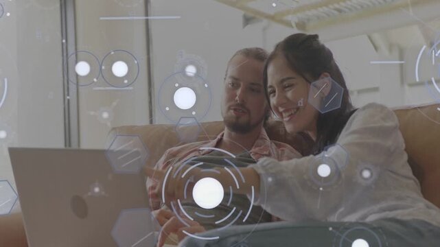 Woman pointing at laptop starting hex circle tech HUD overlay while man watching, planning, smiling