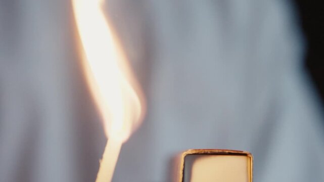 Macro shot of a match being lit through friction with the striking surface 