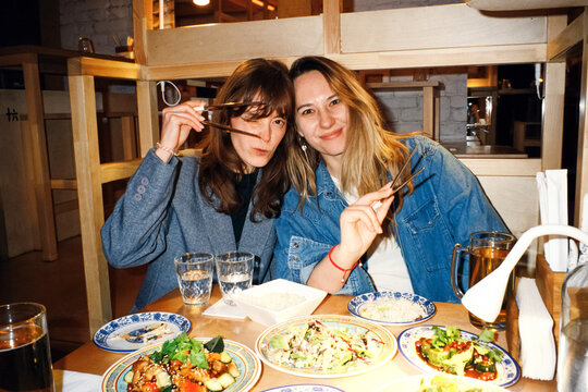 Two Women Enjoying Asian Food Together at Cozy Restaurant