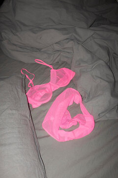 Beautiful hot pink mesh bra panties lingerie on bed sheets with flash