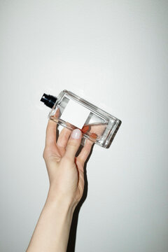 Hand holding classic style mockup perfume bottle with space for text