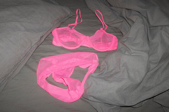 Beautiful hot pink mesh bra panties lingerie on bed sheets with flash