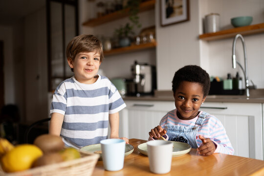 Happy multiracial children sharing meal in kitchen