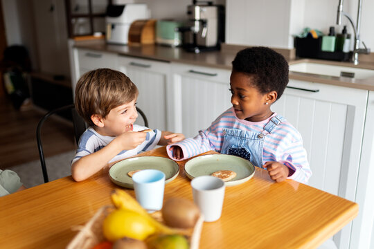 Diverse children eating breakfast together in kitchen