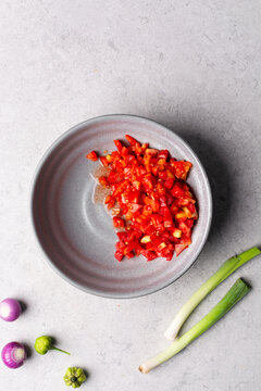 Overhead view of diced tomatoes in a grey bowl, top view of chopped tomatoes on white countertop