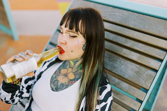 Woman Relaxes and Drinks a Beverage on a Wooden Lounge Chair