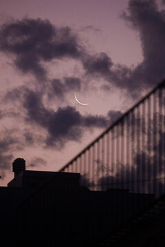 Moon Appears in Purple Sky at Dusk Over City Buildings