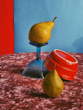 Fruit is placed on a glass and a bowl in a colorful setting