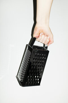 Hand holding shiny silver kitchen tool grater with flashlight