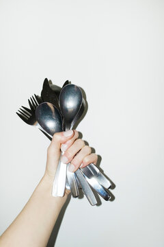 Hand holding punch of shiny silver eating cutlery with flashlight