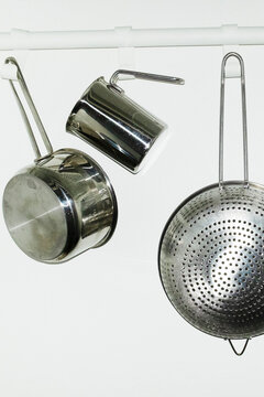 Shiny silver metal kitchen tools hanging from hooks with flashlight