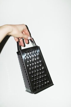 Hand holding shiny silver kitchen tool grater with flashlight
