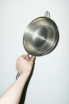 Hand holding shiny silver kitchen tool strainer with flashlight
