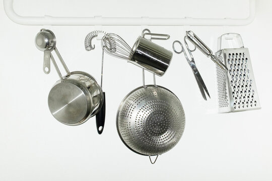 Shiny silver metal kitchen tools hanging from hooks with flashlight