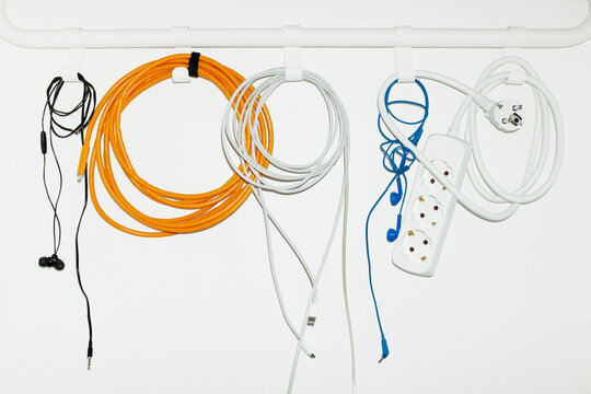 Colourful tech wires and chargers hanging from hooks with flashlight 