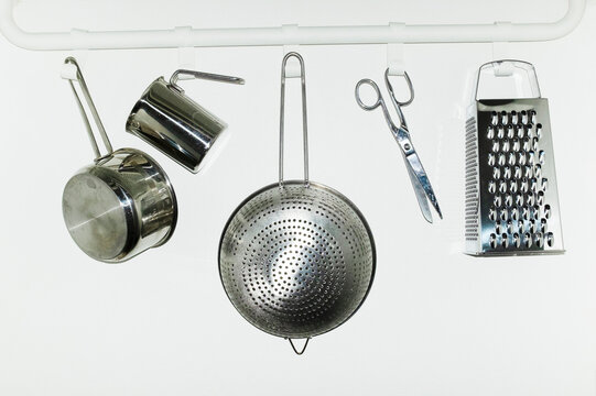 Shiny silver metal kitchen tools hanging from hooks with flashlight