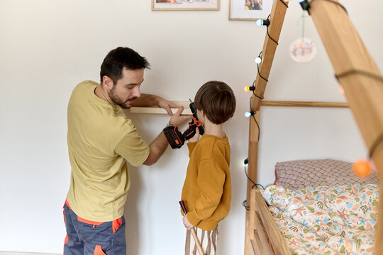 Father and son installing wall shelf together