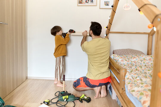Father and son installing wall shelf together