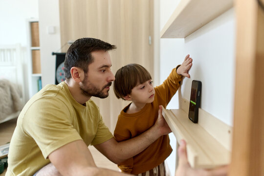 Father and son checking shelf level with smartphone