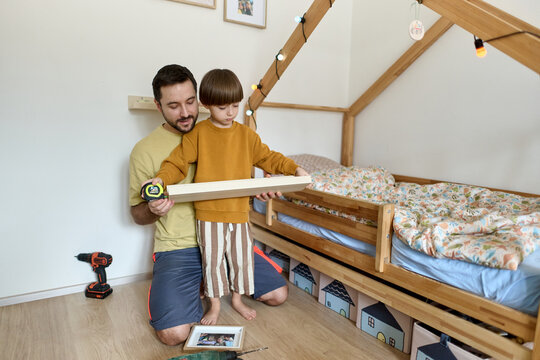 Father and Son Measuring Wooden Shelf Together