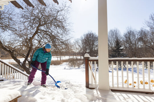 Woman blue shovel snow after snowstorm 
