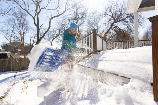 Woman shovels powder snow after snowstorm 