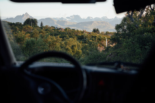 View of scenic Lofoten mountains through parked camper van windshield 