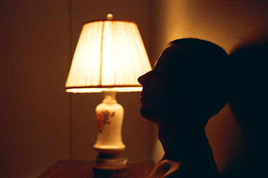 Side silhouette of a man in a bedroom with vintage shade lamp