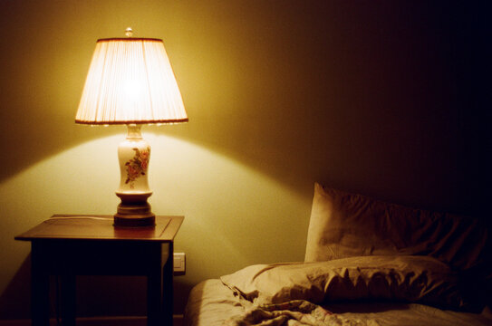 View of wrinkled bedsheets with vintage shade lamp.