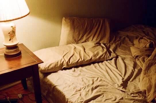 View of wrinkled bedsheets with vintage shade lamp.