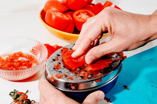 a man grating tomato on a metal grater